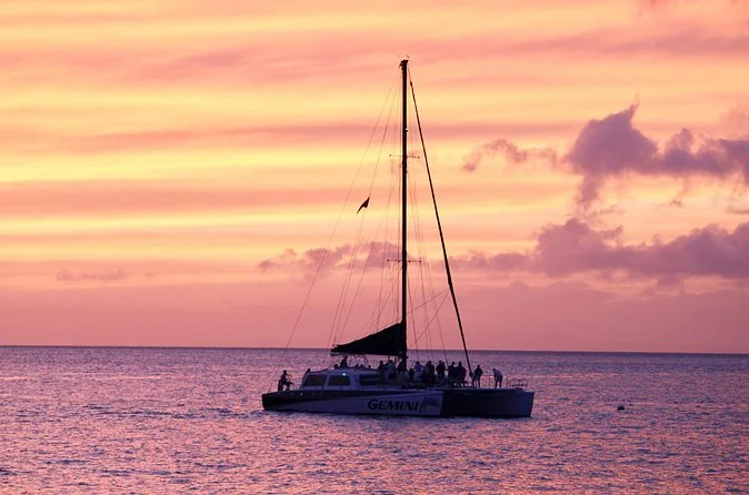 The Gemini catamaran under a pink sunset sky with passengers on deck