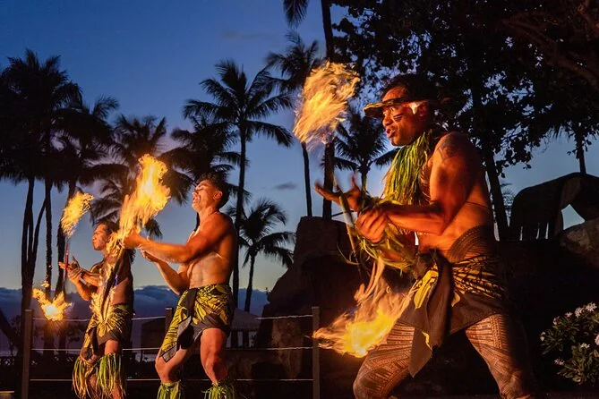 Three fire dancers performing under palm trees at dusk